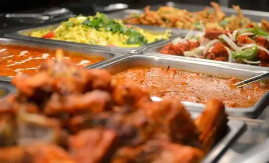 Indian family-style table set with curries, rice, and naan